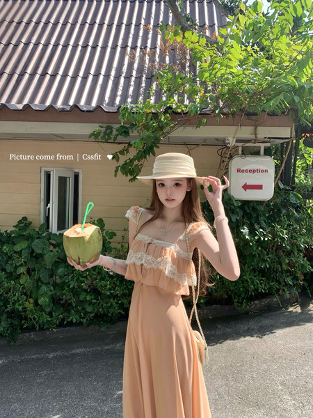 Woman wearing a peach lace-trim maxi dress and straw hat outdoors