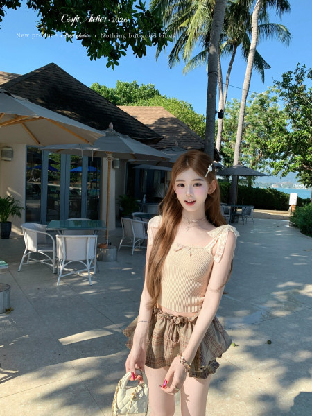 Woman wearing a light knit camisole top and plaid ruffled shorts at a tropical resort