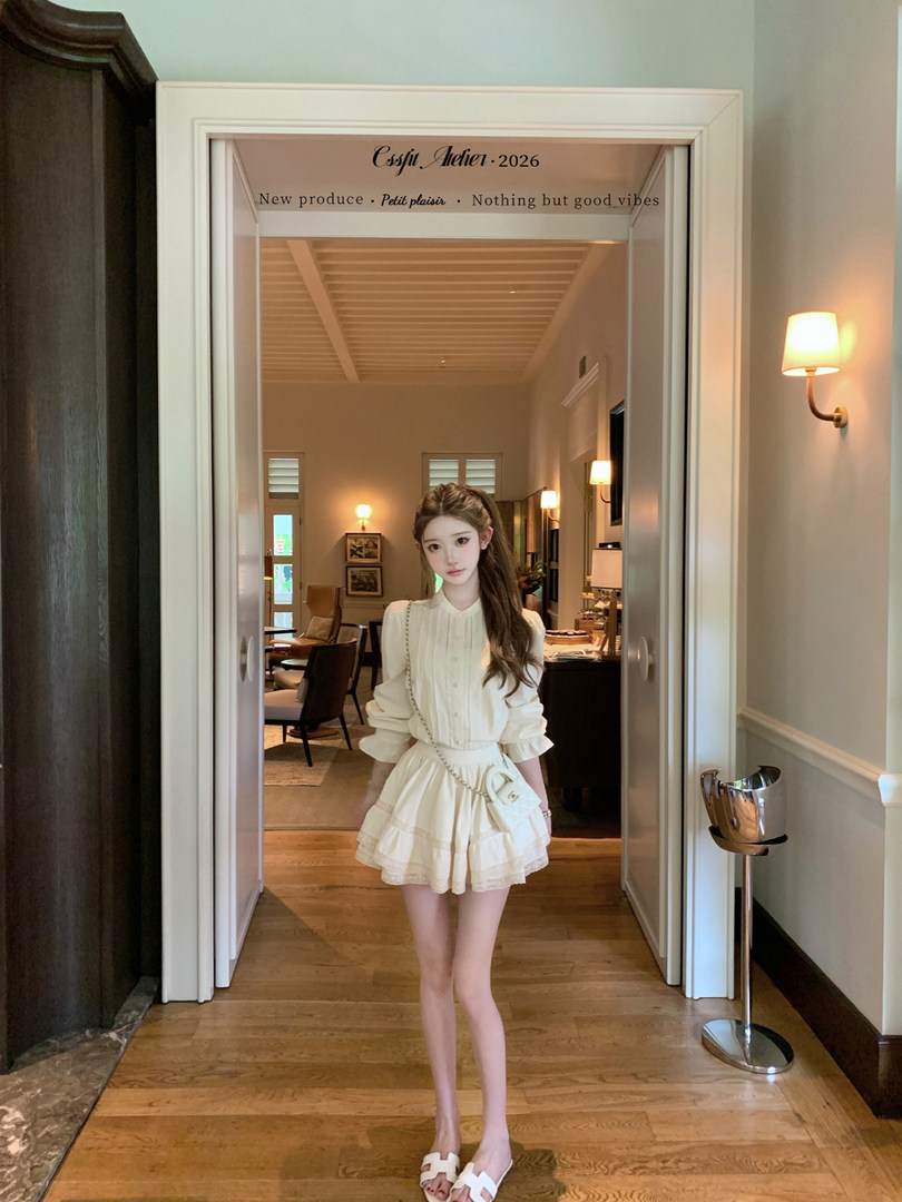 Woman wearing a cream ruffled dress and white sandals indoors