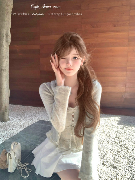 Model wearing a light knit cardigan and white skirt with a small handbag