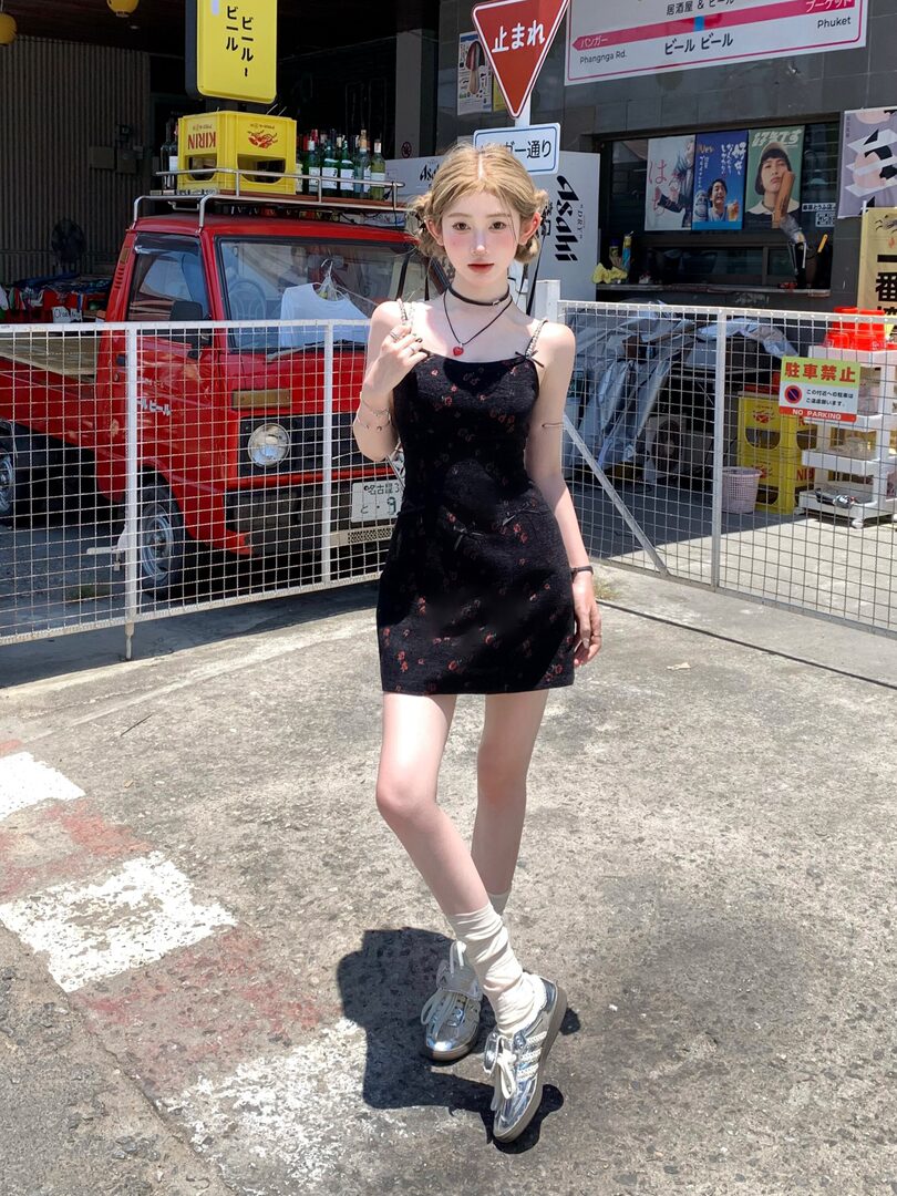 Model wearing a black floral spaghetti-strap mini dress with silver sneakers and white socks outdoors