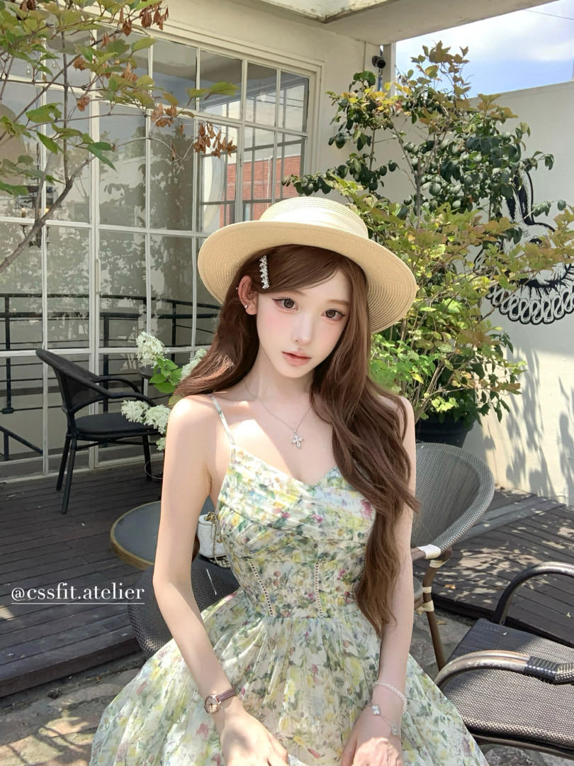 Woman wearing a light floral spaghetti-strap dress and straw hat outdoors