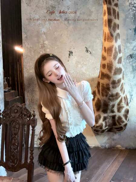 Model wearing a white ruffled short-sleeve blouse and black tiered mini skirt
