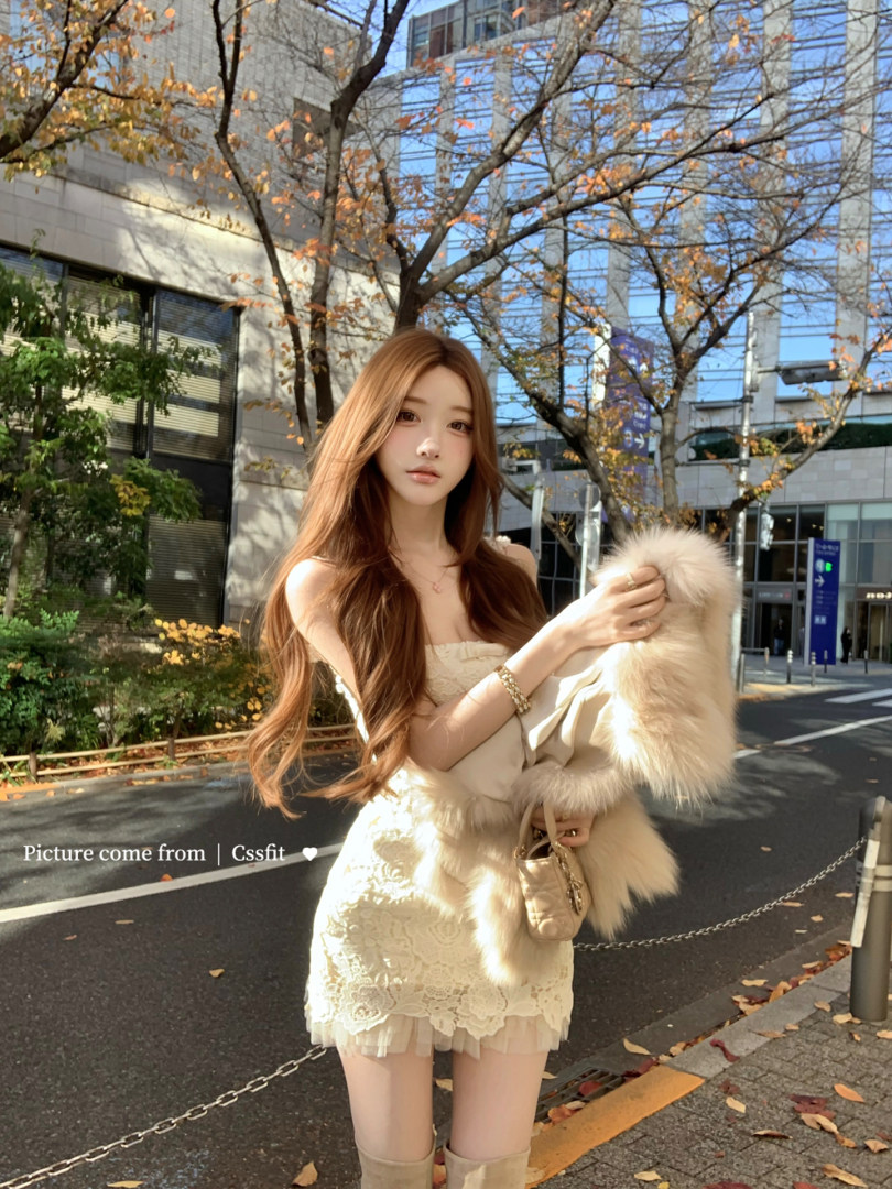 Woman wearing a cream lace mini dress with a faux fur stole outdoors