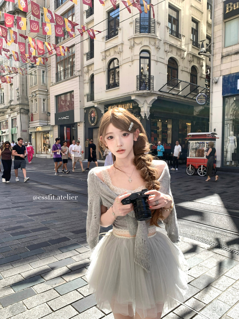 Woman wearing a gray off-shoulder cardigan and white tulle skirt on a city street
