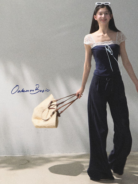 Woman wearing a navy two-piece outfit and holding a woven tote bag