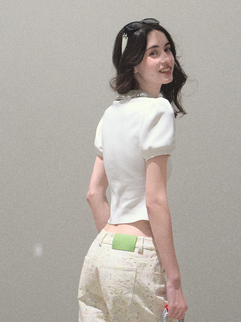 Model wearing a white short-sleeve top with printed pants