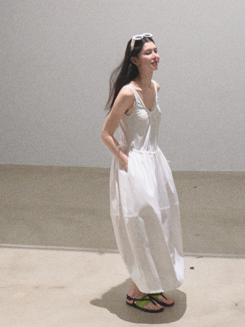Woman wearing a white sleeveless flowy dress or jumpsuit with sandals