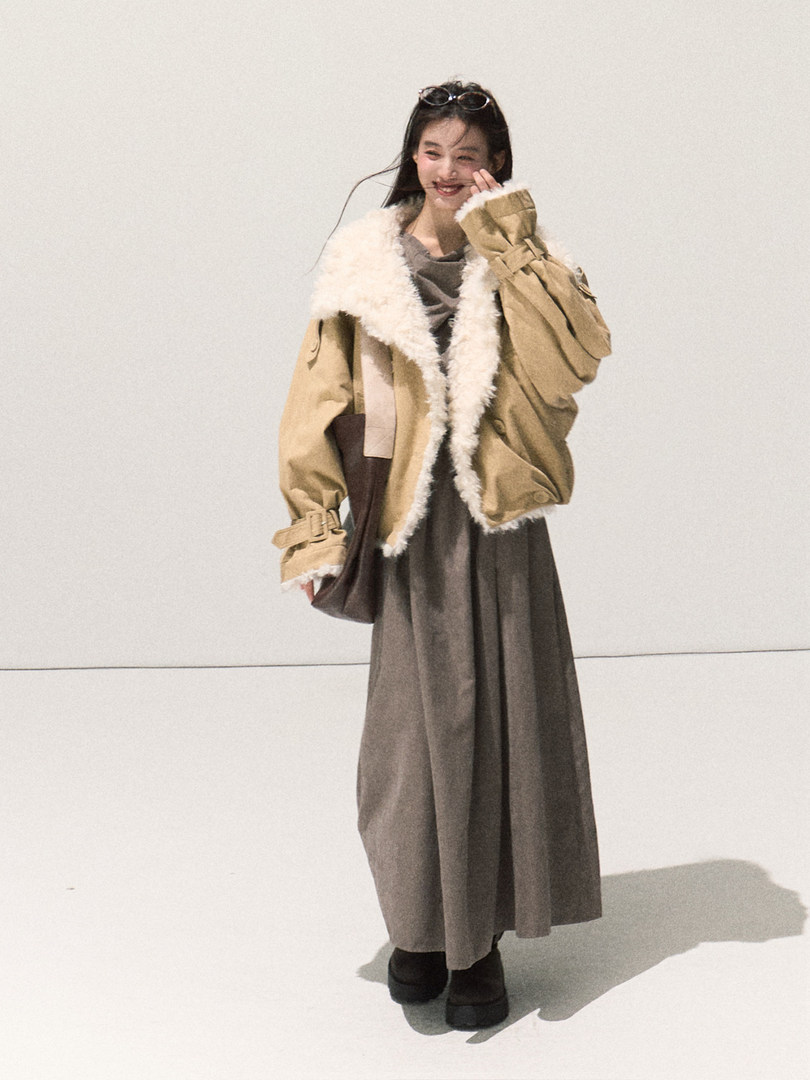 Model wearing a beige fur-trimmed jacket with a long brown skirt