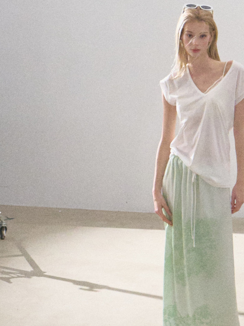 Model wearing a white V-neck top with light green wide-leg pants