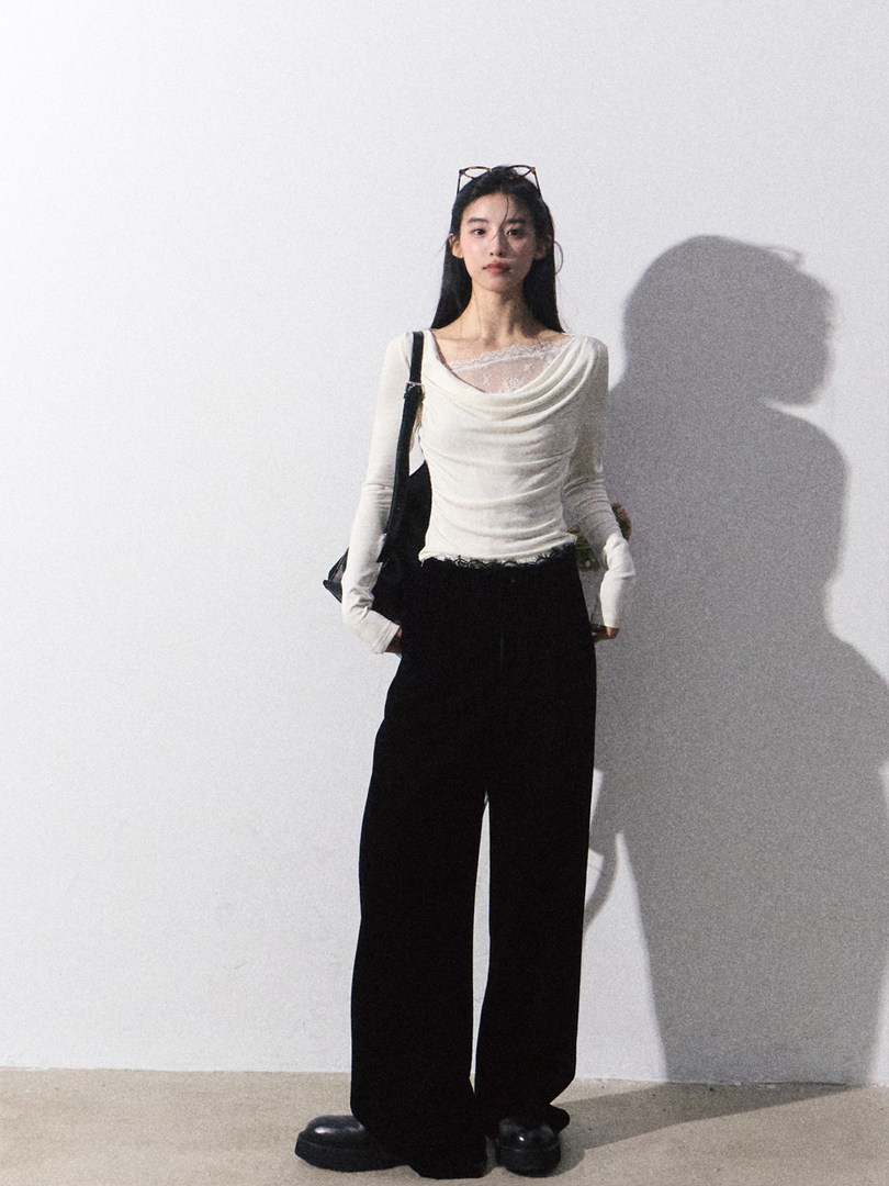 Model wearing a white long-sleeve draped top with black wide-leg pants
