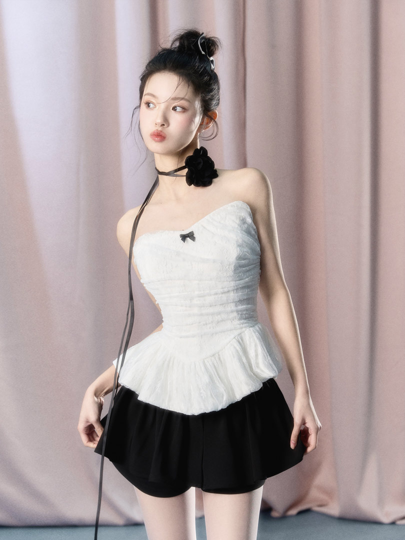 Model wearing a white strapless peplum top with black shorts