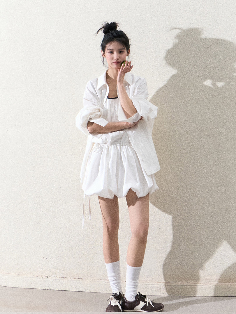 Model wearing a white puff-sleeve blouse and matching shorts outfit
