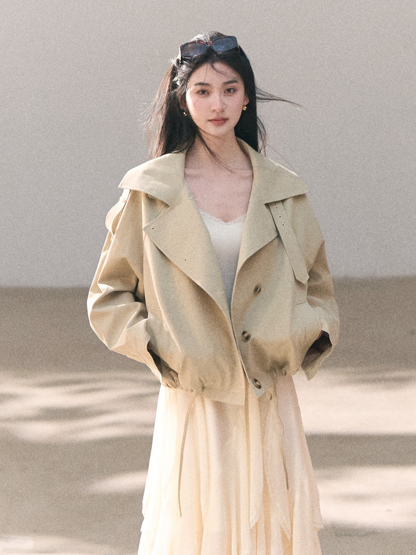 Model wearing a beige trench-style jacket over a cream dress