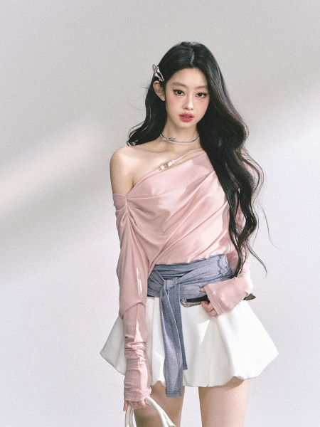 Model wearing a pink off-shoulder top with a white mini skirt and blue wrap belt