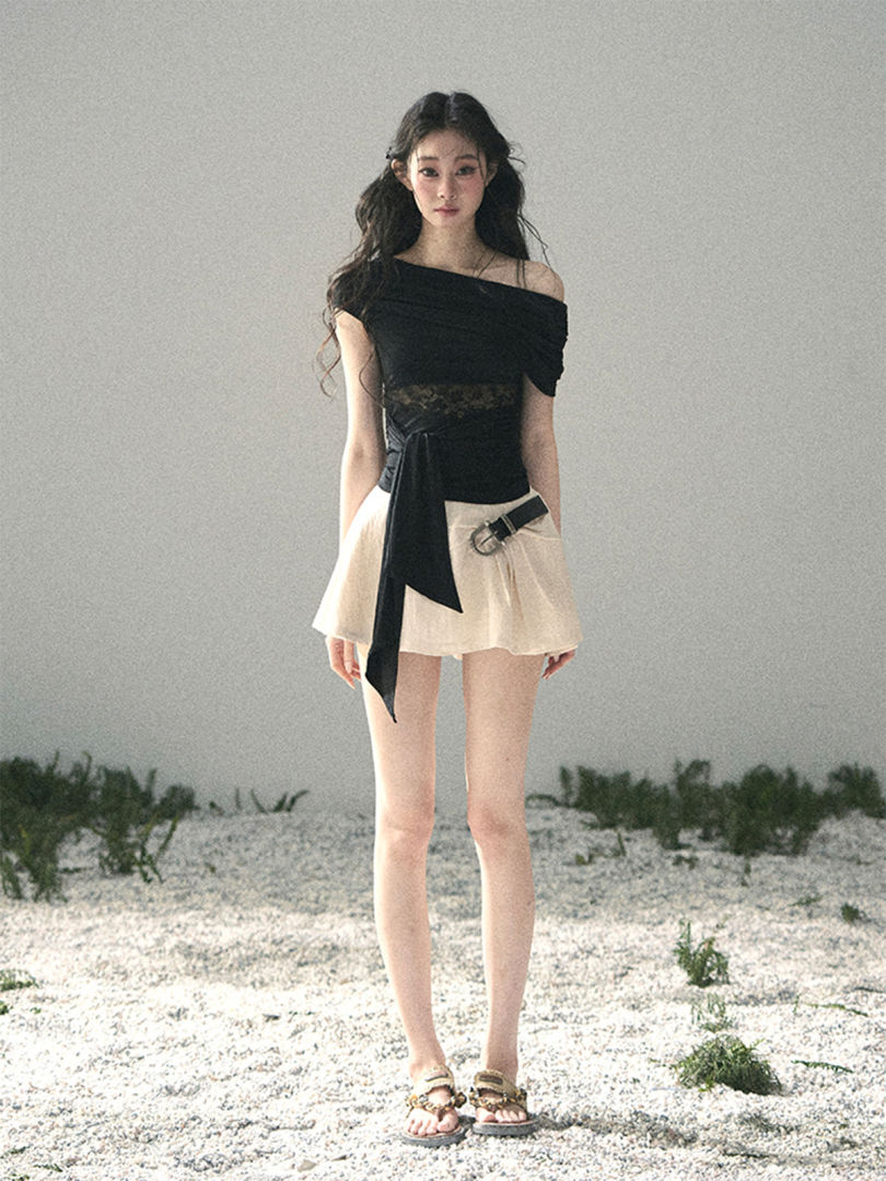 Model wearing a black off-shoulder top with a white mini skirt outdoors