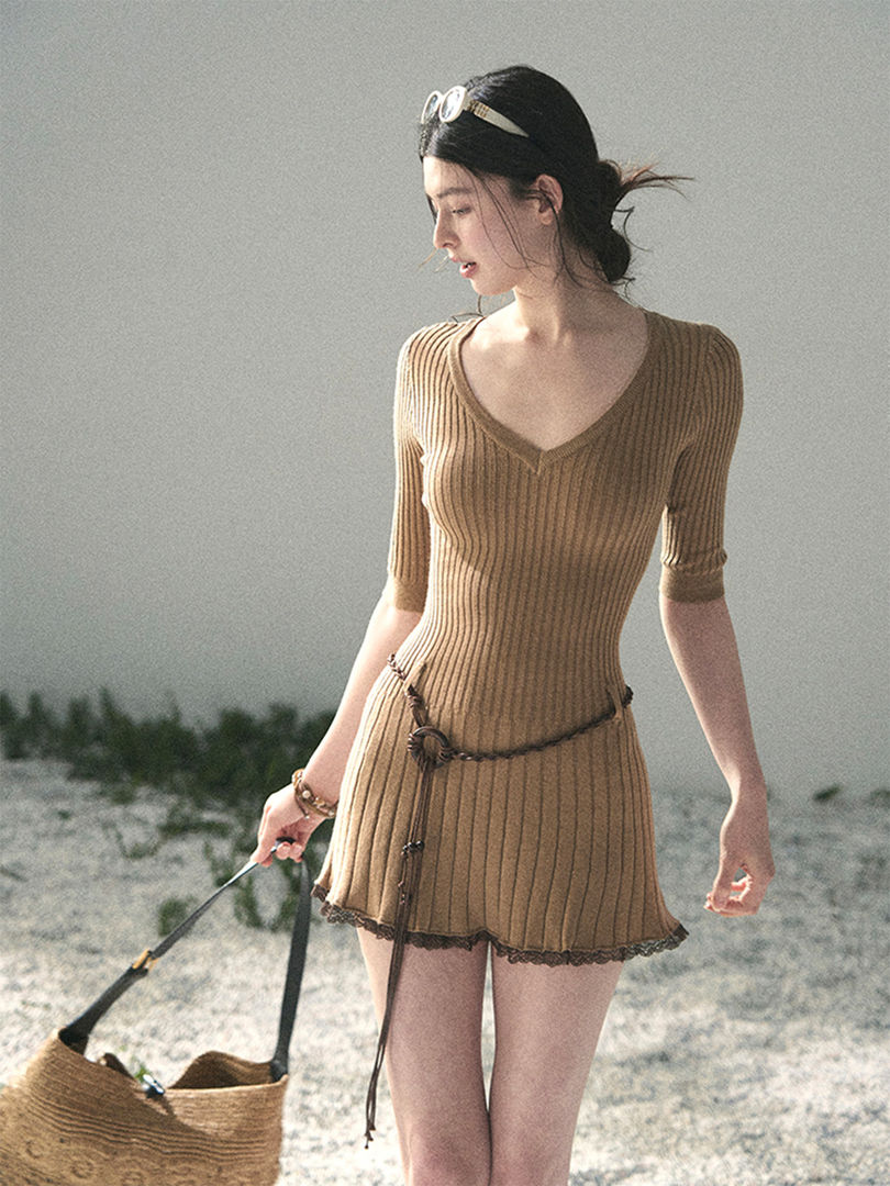 Model wearing a tan ribbed knit short dress with a V-neck and belt detail outdoors
