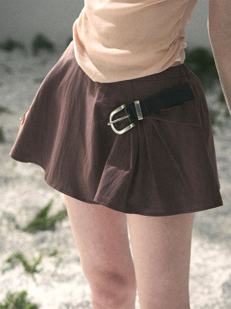 Brown short skirt with a side buckle detail worn by a model outdoors
