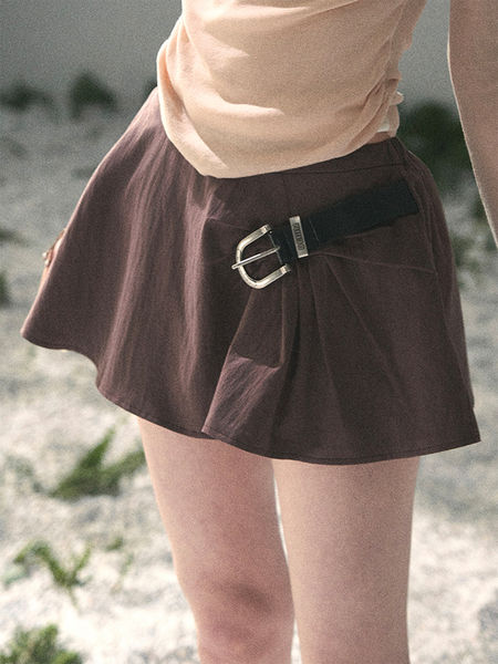 Brown short skirt with a side buckle detail worn by a model outdoors