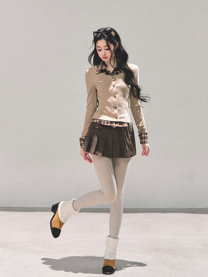 Model wearing a beige plaid layered preppy outfit with tights and loafers