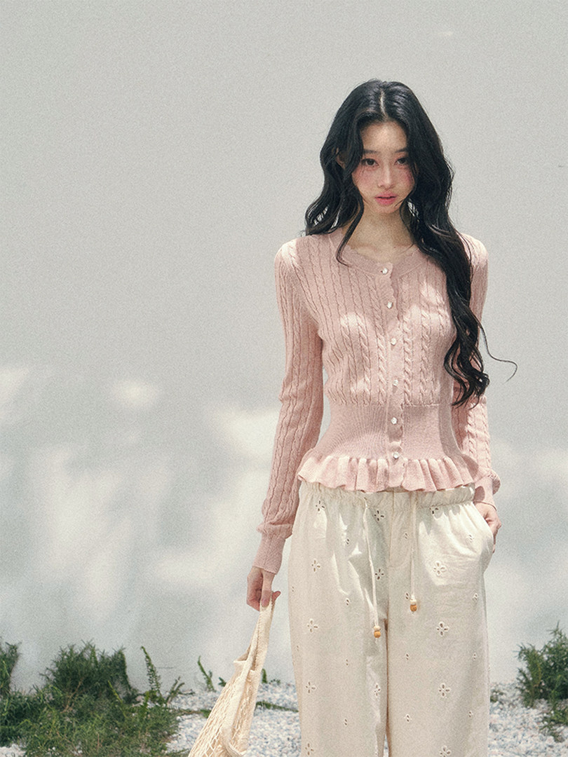 Model wearing a pink knit cardigan with cream eyelet pants