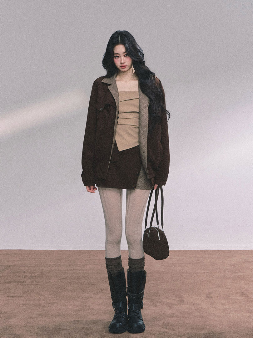Model wearing a layered dark blazer outfit with knee-high boots and a black shoulder bag