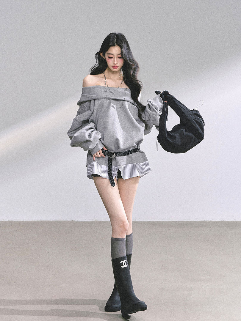 Model wearing a gray off-shoulder sweatshirt with striped shorts and knee-high socks