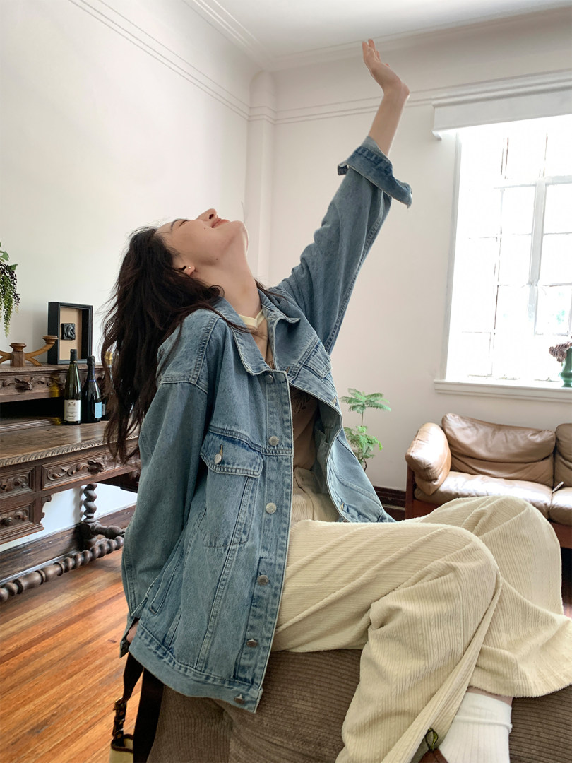 Woman wearing a light blue denim jacket and cream corduroy pants indoors
