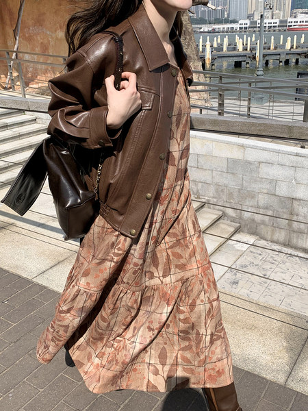 Woman wearing a brown leather jacket over a floral dress outdoors