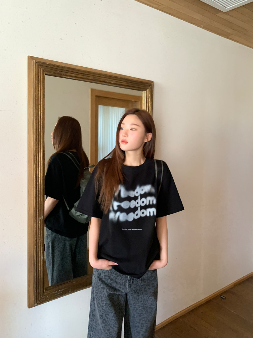 Model wearing a black graphic T-shirt and loose patterned pants in a mirror photo