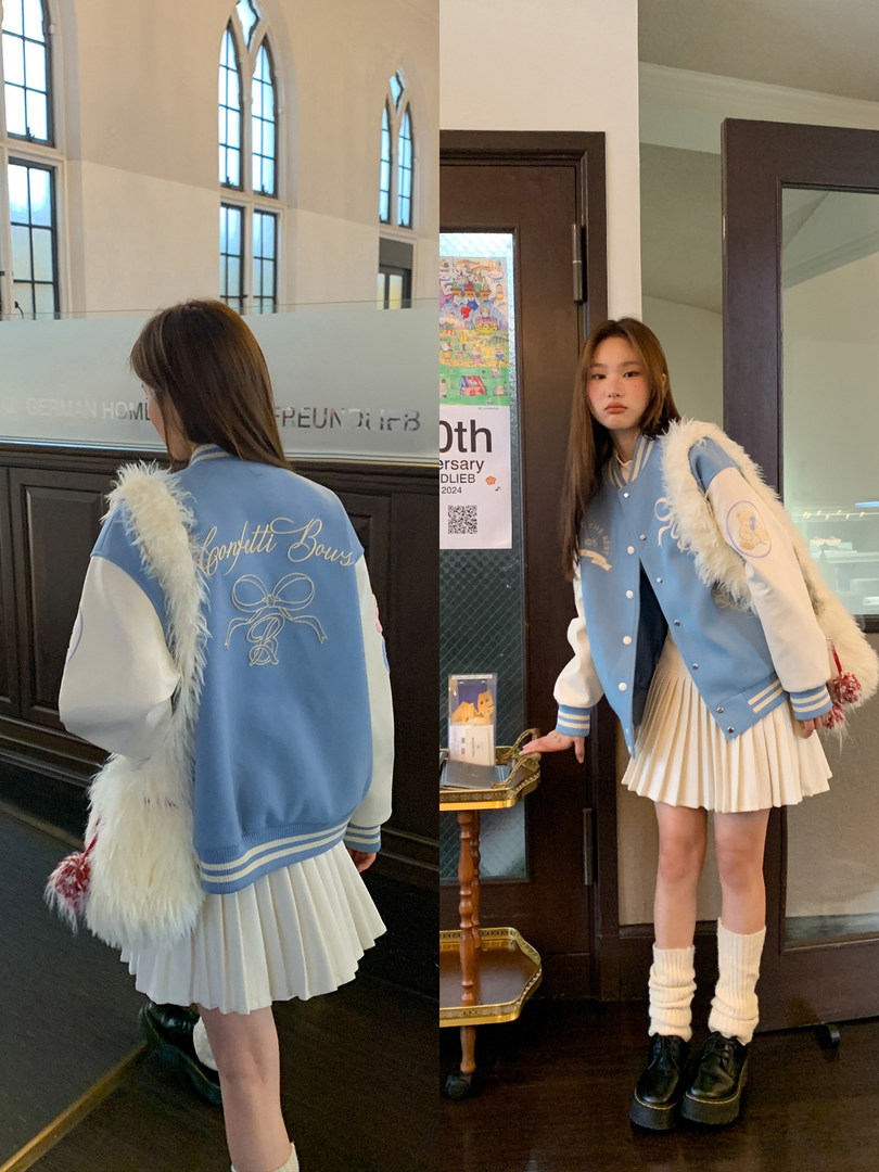 Blue and white varsity jacket with pleated skirt worn by a model