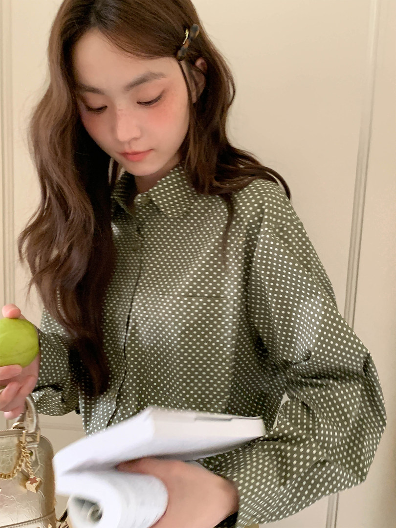 Model wearing a green polka dot button-up shirt