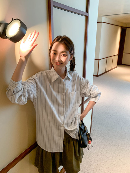 Woman wearing a striped button-up shirt and olive skirt