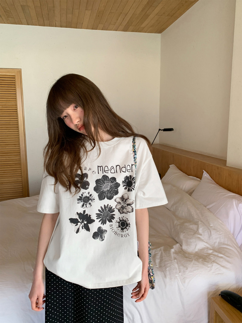 Model wearing a white graphic short-sleeve T-shirt with floral print