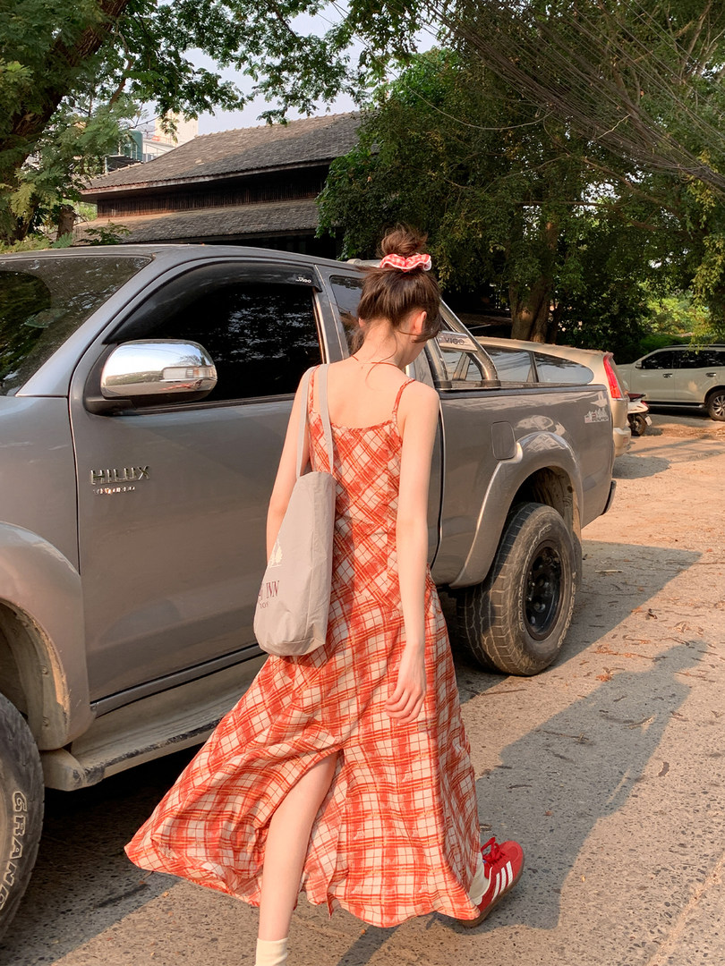Woman wearing a red plaid sleeveless dress outdoors