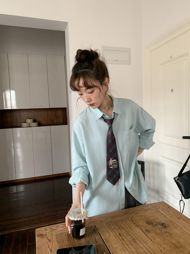 Model wearing a light blue oversized button-up shirt with a striped tie