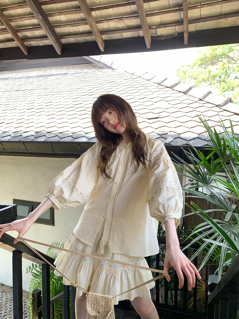 Model wearing a cream embroidered puff-sleeve outfit with a matching skirt