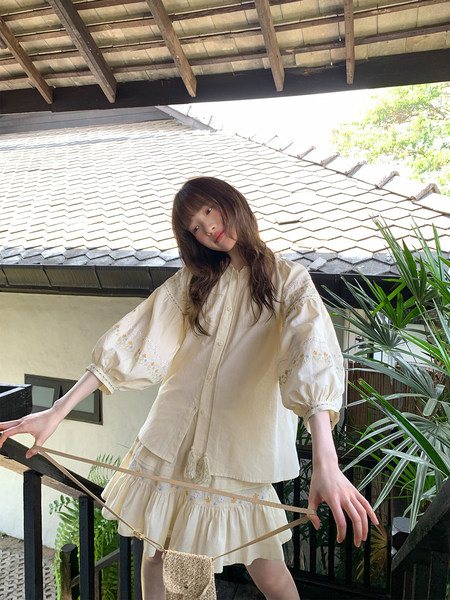 Model wearing a cream embroidered puff-sleeve outfit with a matching skirt