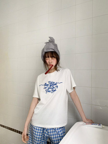 Model wearing a white graphic T-shirt with blue checkered shorts