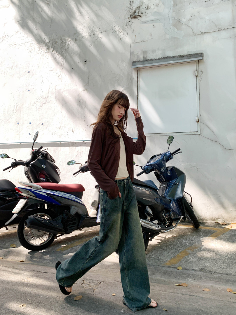 Woman wearing a brown cardigan with cream top and baggy jeans outdoors