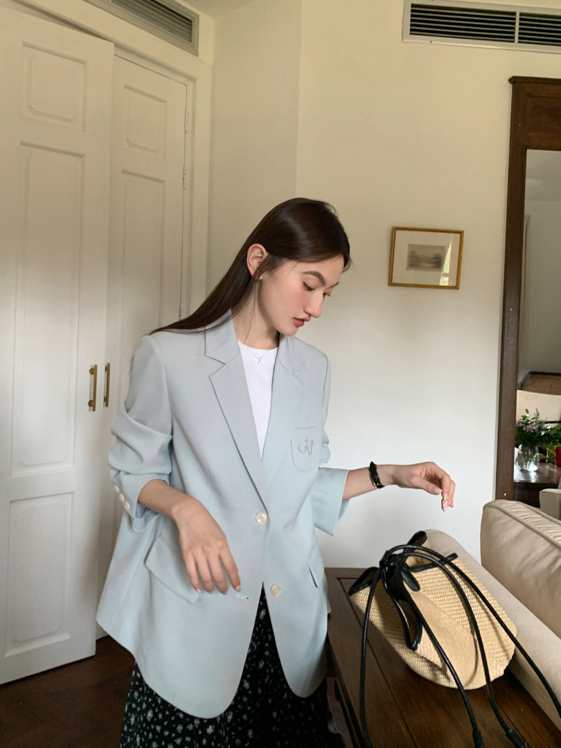 Woman wearing a light blue blazer with a black skirt indoors