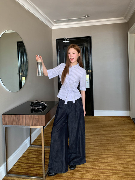Model wearing a light striped peplum blouse with wide-leg dark denim pants