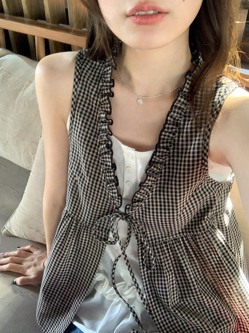 Woman wearing a black-and-white gingham ruffle tie vest over a white top