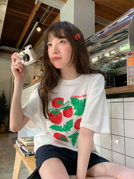 White graphic t-shirt with red tomato print worn by a model