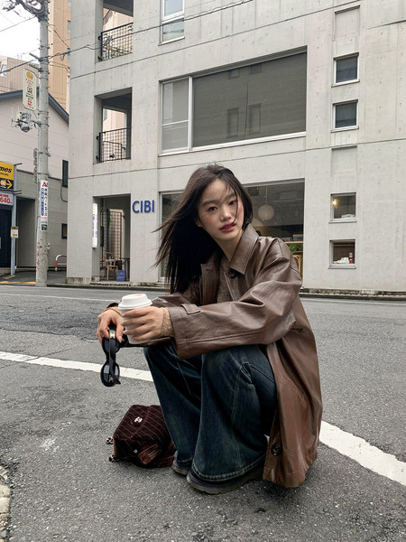 Woman wearing a brown leather jacket and wide-leg jeans on a city street