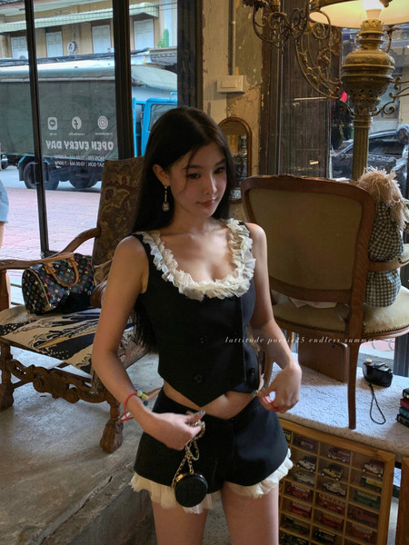 Woman wearing a black ruffled two-piece outfit in an indoor setting