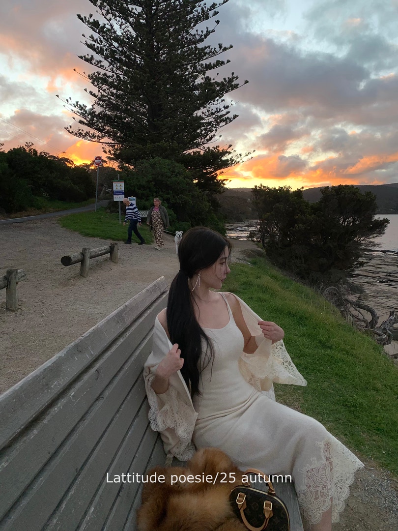 Woman wearing a cream lace-trim dress outdoors at sunset