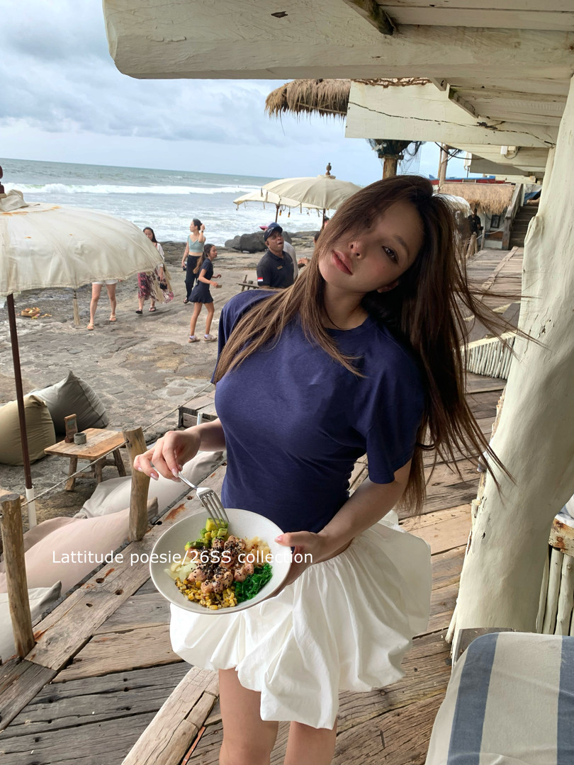 Woman wearing a navy top and white skirt at a beachside setting