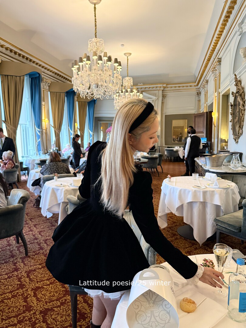 Woman wearing a black long-sleeve dress in an elegant restaurant setting