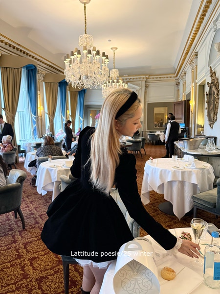 Woman wearing a black long-sleeve dress in an elegant restaurant setting